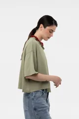 Remera verde militar de corte holgado y diseño amplio, con mangas cortas, hombros caídos, largo levemente cropped y detalle de broderie en el frente.