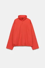 Chaqueta roja Fruit of the Loom x Zara con cuello subido, cierre frontal con cremallera, mangas largas y bolsillos laterales de vivo. Cuenta con bajo ajustable con cordón elástico.
