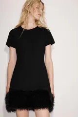 Vestido corto de punto color negro, con cuello redondo, manga corta y bajo con aplicación de pelo sintético a tono.