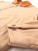 Campera color beige de gabardina 100% algodón, con cuello marrón de pana, cierre metálico reforzado, bolsillos internos y externos, forro de paño, puños y cintura ajustables.