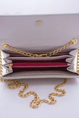 Cartera tipo sobre color beige con textura granulada y correa de cadena dorada.