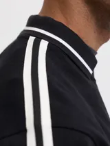 Buzo de manga larga color negro con cuello tipo polo y detalles de líneas blancas en cuello y puños. Presenta un diseño gráfico estampado en el frente con la inscripción 'CHALÉT CLUB' y detalles deportivos. Confeccionado en tejido suave con ajuste holgado.