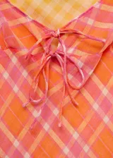 Vestido corto de tirantes finos dobles, con diseño recto y escote de pico. Presenta un estampado de cuadros en tonos naranja y rosado, con un lazo decorativo en el centro del pecho.