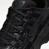 Zapatilla deportiva Nike P-6000, completamente negra, con paneles superpuestos de malla y material sintético brillante, y logo Swoosh en el lateral.