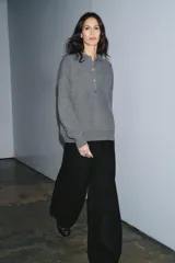 Sweater de punto liso color gris melange, con cuello polo, manga larga y cierre frontal con botones. Presenta puños y ruedo acanalados.