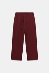 Pantalón de tiro medio y pernera recta con textura, de color marrón. Cuenta con cintura elástica y cordón ajustable con abalorios decorativos.