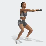 Bralette deportivo Adidas Hyperglam color gris oscuro con tirantes finos ajustables. Presenta detalles de costuras curvas y una banda elástica inferior en color blanco con el logo de Adidas.