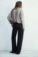 Camisa fluida de corte oversize confeccionada en mezcla de viscosa, con diseño de rayas verticales finas en tono beige sobre fondo blanco. Presenta cuello solapa, cierre frontal con botones, manga larga con puños y un bolsillo de plastrón en el pecho.