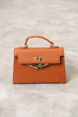 Cartera de mano color verde esmeralda, con herrajes dorados y asa corta.