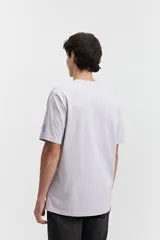 Remera de manga corta color lila, de corte regular y escote redondo, con estampa frontal de líneas topográficas y texto.