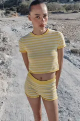 Top corto de punto con diseño a rayas horizontales en color amarillo y blanco, cuello redondo y manga corta.