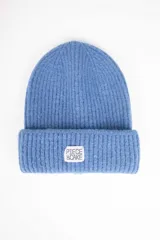 Gorro de lana tejido color celeste con etiqueta blanca con logo de la marca en el borde.