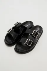 Sandalias planas de mujer con doble tira ancha en el empeine, hebillas metálicas plateadas y textura símil cocodrilo.