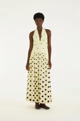 Vestido largo amarillo con estampado de lunares negros, escote halter y falda amplia.
