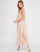 Pantalón palazzo de tiro alto color beige, confeccionado en mezcla de lino y viscosa, con silueta suelta y fluida, cintura elastizada, bolsillos delanteros aplicados y ruedo festoneado de corte tobillero.