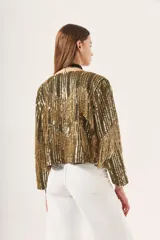 Saco corto dorado con bordado de lentejuelas y canutillos, escote en V y mangas largas.