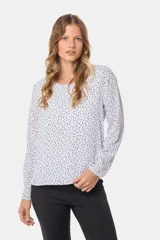 Blusa blanca con estampado de lunares negros, de manga larga y cuello redondo con abertura en la espalda.