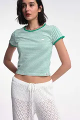 Remera baby blanca de algodón, de corte cropped al cuerpo y mangas cortas. Presenta ribetes negros en contraste en el cuello redondo y los puños, con un estampado localizado de un ají rojo con la inscripción 'Pimentón' en el centro del pecho.