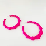 Aros tipo argolla de resina color fucsia con diseño de bambú.