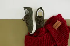 Zapatillas de gamuza verde oliva con cordones marrones y suela de goma color crema.