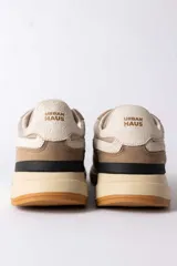 Championes urbanos de diseño técnico, combinando paneles de gamuza y tela en tono verde oliva con detalles en beige y negro. Presentan una suela de plataforma en color crema con base dentada en tono caramelo.