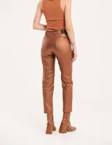 Pantalón negro estilo jeanero confeccionado en gabardina elastizada con terminación metalizada, pierna recta con largo por arriba del tobillo, cierre delantero y botón.