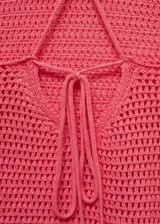 Top tejido de punto fino color rosado, con cuello halter, tirantes finos y espalda descubierta con cierre de lazo.
