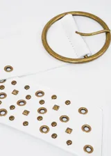 Cinto blanco de cuero sintético con hebilla redonda dorada y tachas doradas de diferentes formas.