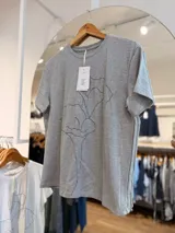 Remera gris melange de manga corta y cuello redondo, con estampado lineal negro de una flor en el frente.