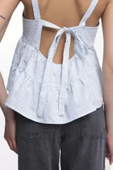 Top de tirantes con escote recto y diseño peplum con dos volados horizontales. Confeccionado en tejido de algodón con textura de microcuadros.