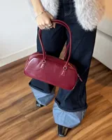 Cartera tipo baguette de cuero sintético color borgoña, con doble asa corta y cierre superior con cremallera.