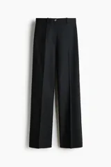 Pantalón negro de corte bootcut, con tiro alto, trabillas para cinturón y cierre frontal con botón y cremallera. Cuenta con pliegues marcados al frente y bolsillos simulados con solapa en la parte delantera.