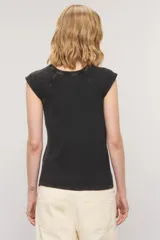 Remera color blanco roto, de calce slim, cuello redondo y manga corta con detalle de hombreras y pequeño bordado en el centro del pecho.