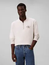 Buzo Calvin Klein de felpa de algodón color blanco off-white, con cuello alto, cierre de media cremallera y manga larga con puños acanalados. Cuenta con el logo de la marca bordado en el pecho.