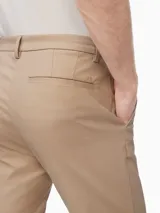 Pantalón de vestir color beige, corte slim, confeccionado en mezcla de algodón elástico. Presenta cierre de botón y cremallera, bolsillos delanteros y traseros.