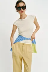 Pantalón de tiro medio color amarillo, con cintura elástica, bolsillos de plastrón en el delantero y pernera holgada que se estrecha hacia el tobillo. Cuenta con cierre frontal de cremallera y botón.