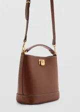 Bolso tipo bucket de tamaño pequeño, color marrón, con asa corta superior y cierre metálico frontal. Incluye detalles de costuras visibles y herrajes en tono dorado.