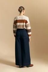 Jean de corte wide leg y tiro alto, color negro con costuras en contraste color ocre. Presenta bolsillos delanteros y traseros con detalle de pespunte, y ruedo ancho con costura decorativa.