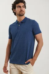 Remera polo de manga corta en color azul oscuro con estampado de pequeños puntos celestes. Presenta cuello clásico, cierre frontal con dos botones y terminaciones acanaladas en las mangas.