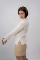 Polera gris de tejido de punto grueso, con cuello alto y mangas largas.