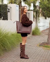 Botas de caña alta confeccionadas en cuero color marrón caoba. Presentan un diseño robusto con tres hebillas metálicas ajustables en el lateral superior y una correa con hebilla y remaches metálicos en la zona del tobillo. Cuentan con un taco bajo cuadrado y suela de goma resistente.