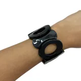 Pulsera elástica negra con eslabones grandes de resina con forma de círculos unidos entre sí.
