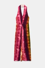 Vestido midi de cuello halter y escote en V, con diseño tie-dye en tonos fucsia, borgoña y verde. Presenta un nudo decorativo en el delantero, espalda descubierta y abertura frontal en el bajo.