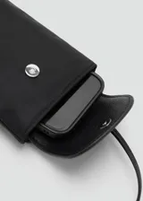 Portacelular de nailon negro con solapa de cuero sintético texturizado, cierre de botón a presión metálico y correa larga fina para colgar.