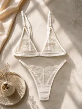 Conjunto de lencería compuesto por un bralette de encaje con breteles regulables y cierre frontal, y una tanga colaless de encaje con laterales regulables.