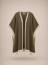 Ruana de lana merino y mohair color verde oliva, con diseño de caída fluida y terminaciones artesanales de encaje tejido en color crema en los bordes.