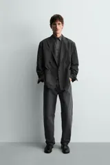 Blazer cruzado de corte relajado, confeccionado en mezcla de algodón y lino, en color gris oscuro. Presenta solapas de pico, bolsillos de parche en la cadera y cierre frontal de doble botonadura.