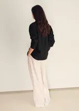 Camisa de lino color negro, de diseño oversize, con cuello camisero, cierre frontal de botones y manga larga con puños abotonados.