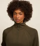 Buzo deportivo verde oliva de microfibra pesada, con cuello alto con cremallera, recorte en los hombros y dos aberturas en la parte de abajo.