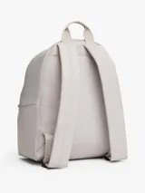 Mochila de diseño redondeado en color gris claro, confeccionada en poliéster texturizado. Cuenta con un compartimento principal con cierre, un bolsillo exterior con cremallera en la parte frontal y un bolsillo interior de malla abierto. Posee asa superior y correas ajustables y acolchadas. Lleva un parche tejido de Tommy Jeans en la parte delantera.